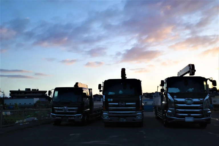 夕暮れの車庫に並ぶトラック